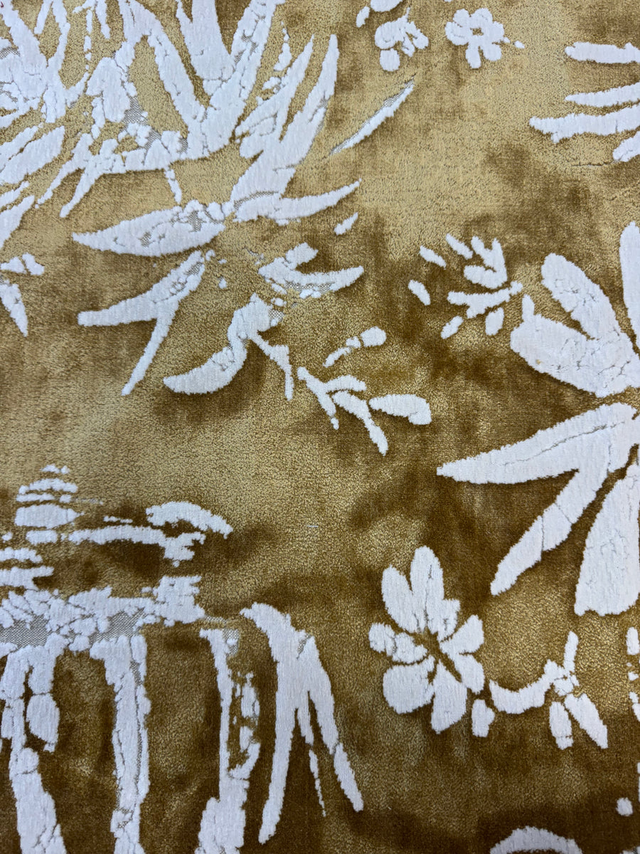 Close-up of a fabric with white floral and leaf patterns on a brown background