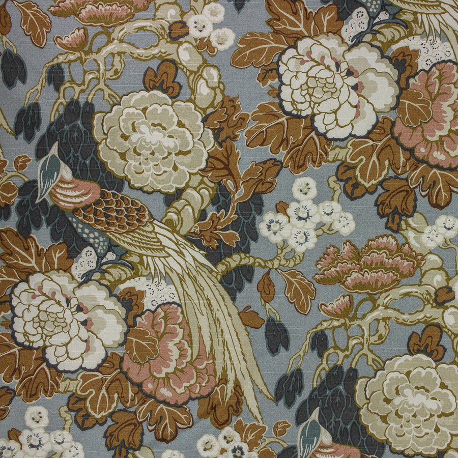 Close-up of floral and bird pattern fabric with brown, white, and pink colors on a blue background.