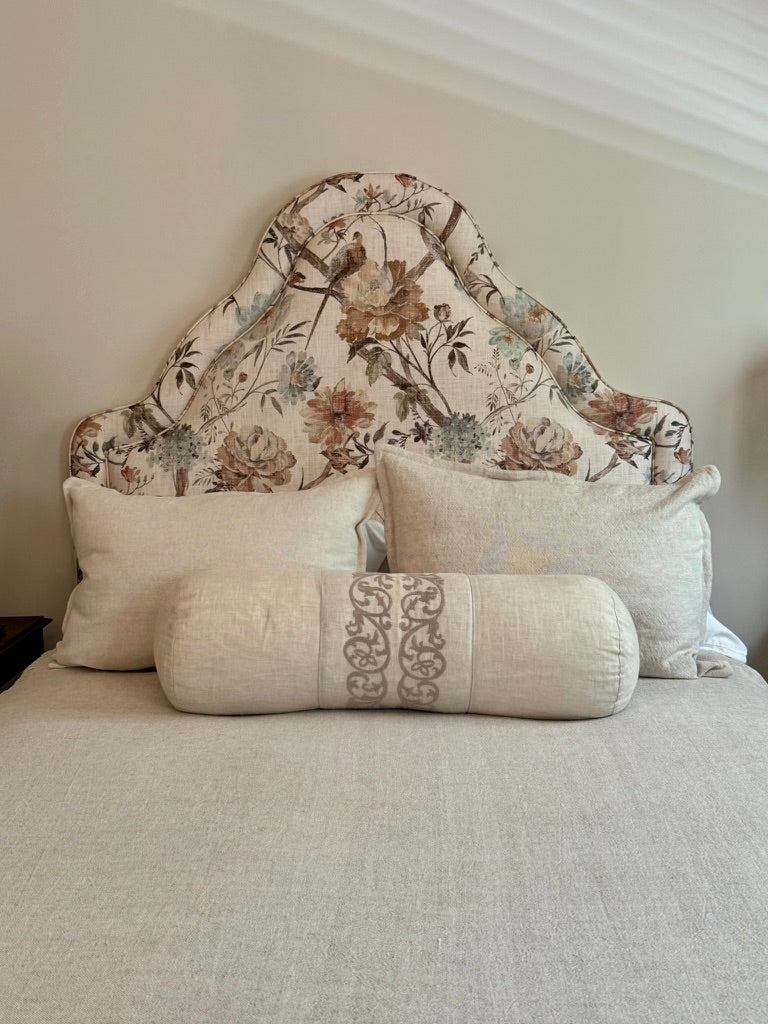floral fabric headboard with beige pillows and bedding