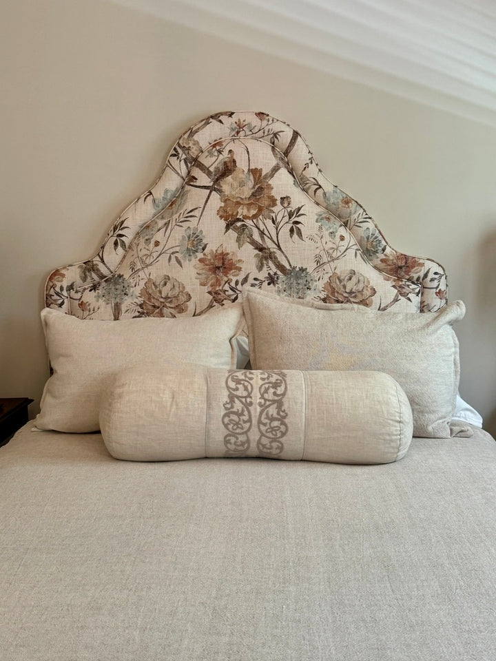 floral fabric headboard with beige pillows and bedding