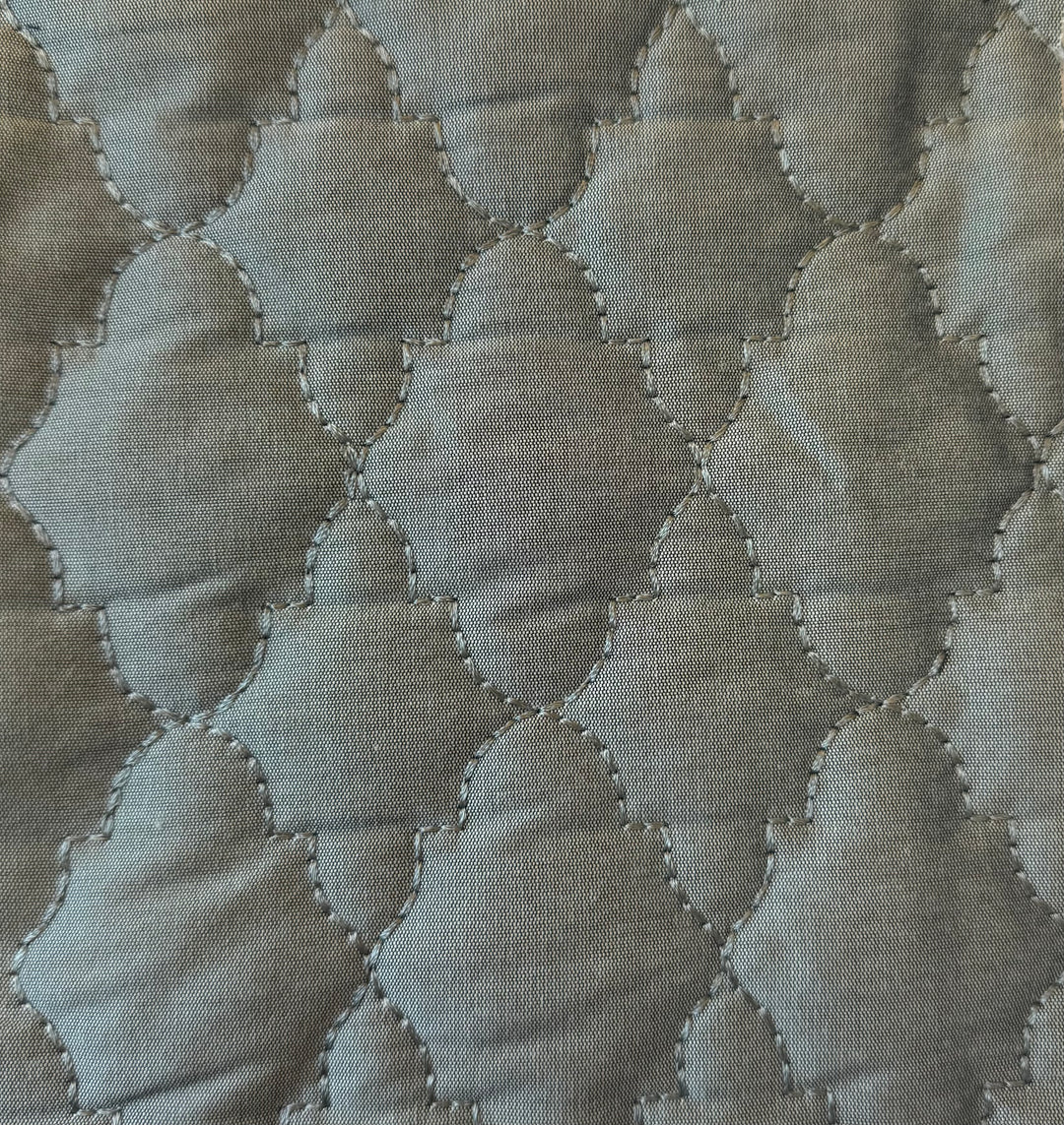 Quilted fabric with a geometric pattern in shades of green.
