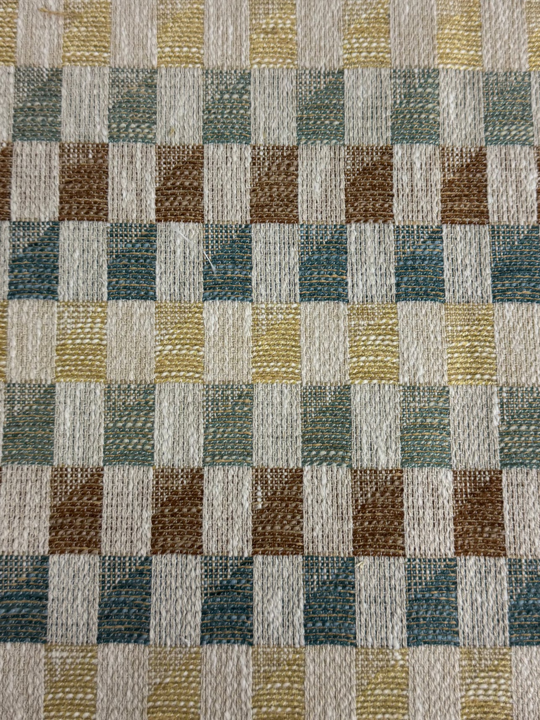 Checkered fabric swatch with brown, green, and beige squares on a white background