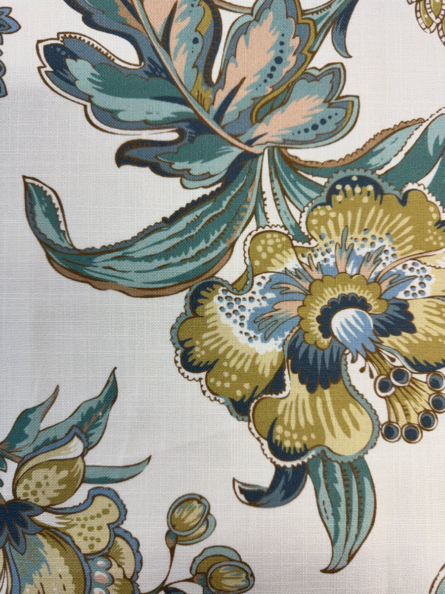 Close-up of a floral pattern with green, blue, and beige colors on a fabric background.