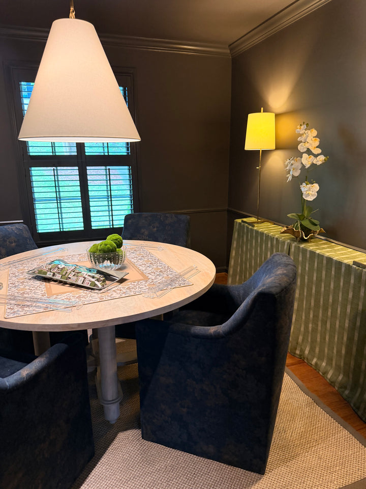 Dining room with round table, chairs, and decorative elements.