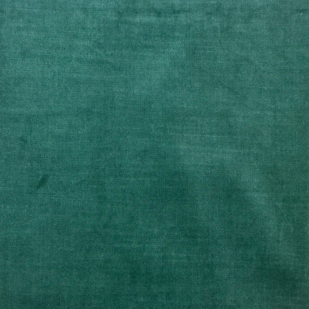 A close-up of a textured teal green fabric surface with subtle woven detail and soft shading.