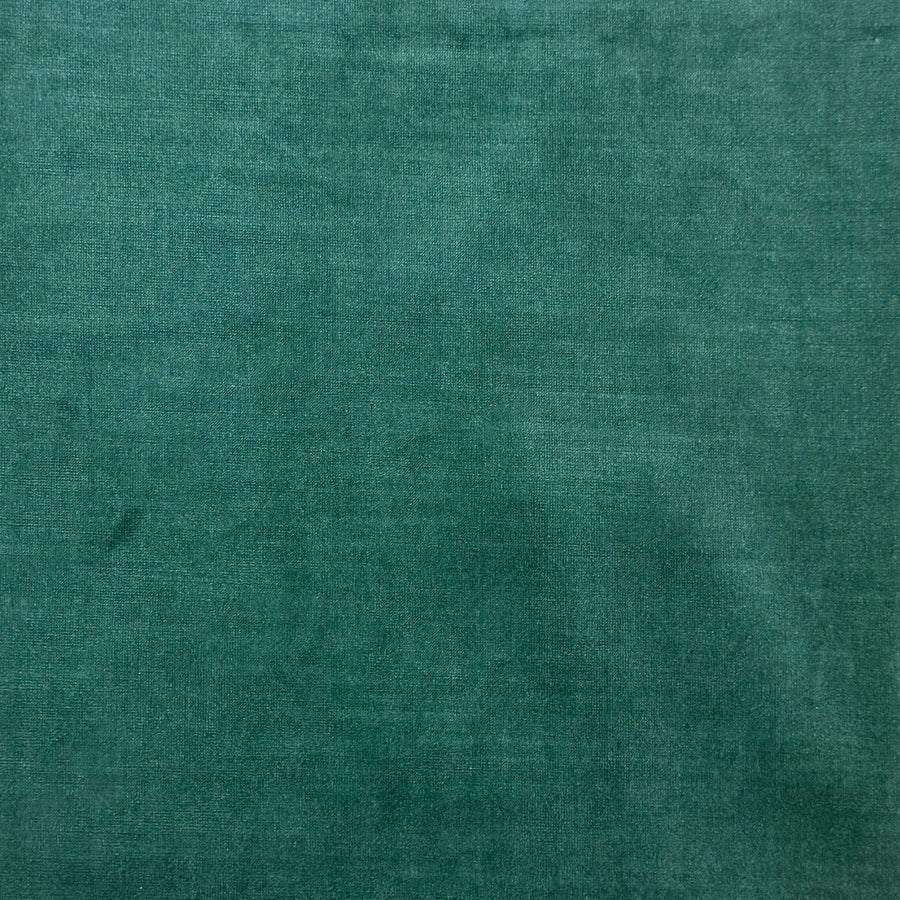 A close-up of a textured teal green fabric surface with subtle woven detail and soft shading.