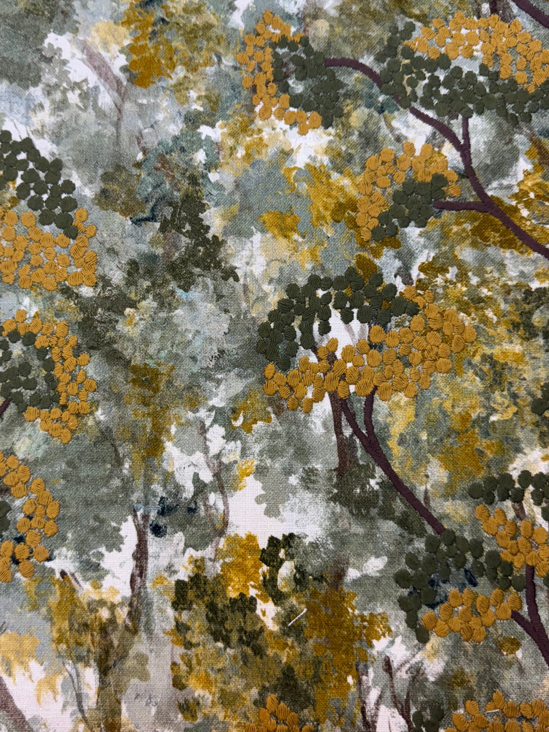 Close-up of a fabric with a nature-inspired pattern featuring green, yellow, and brown colors.