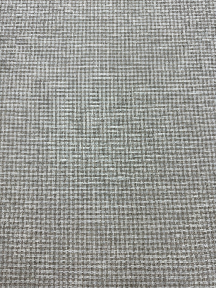 A close-up view of a fabric with a checkered pattern, primarily in beige and brown tones.