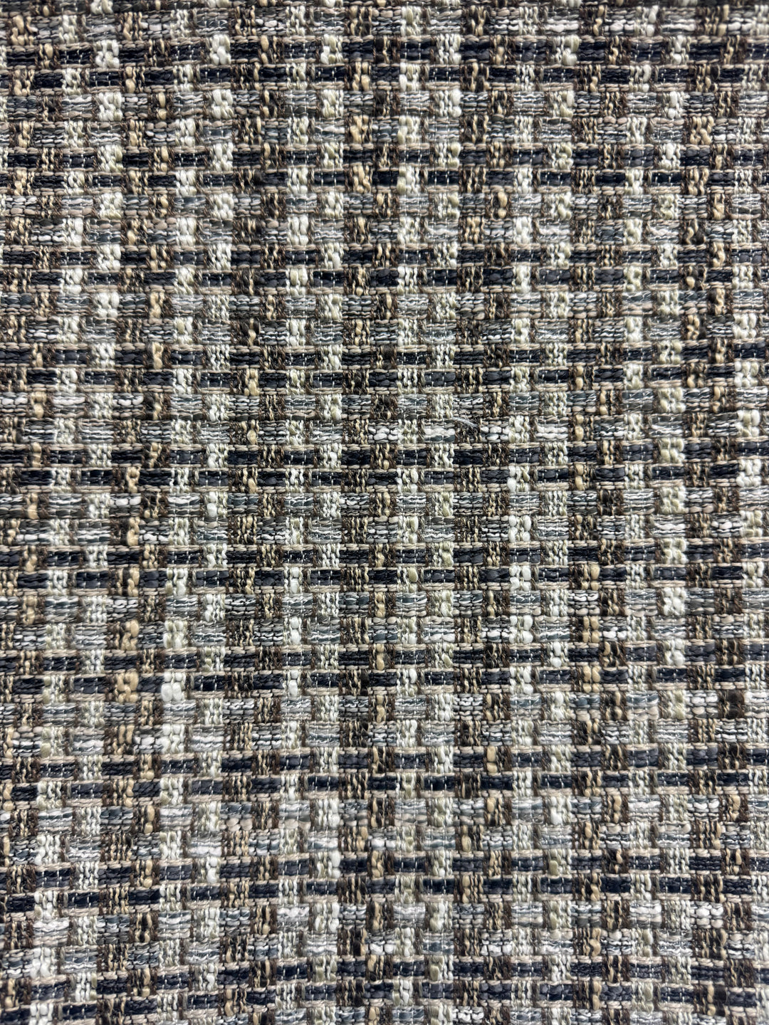 Textured fabric with a checkered pattern in black, white, and brown.