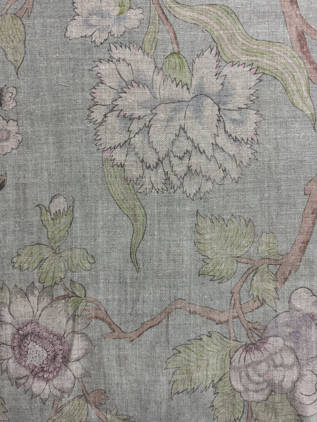 Floral patterned fabric with green leaves and purple flowers on a gray background