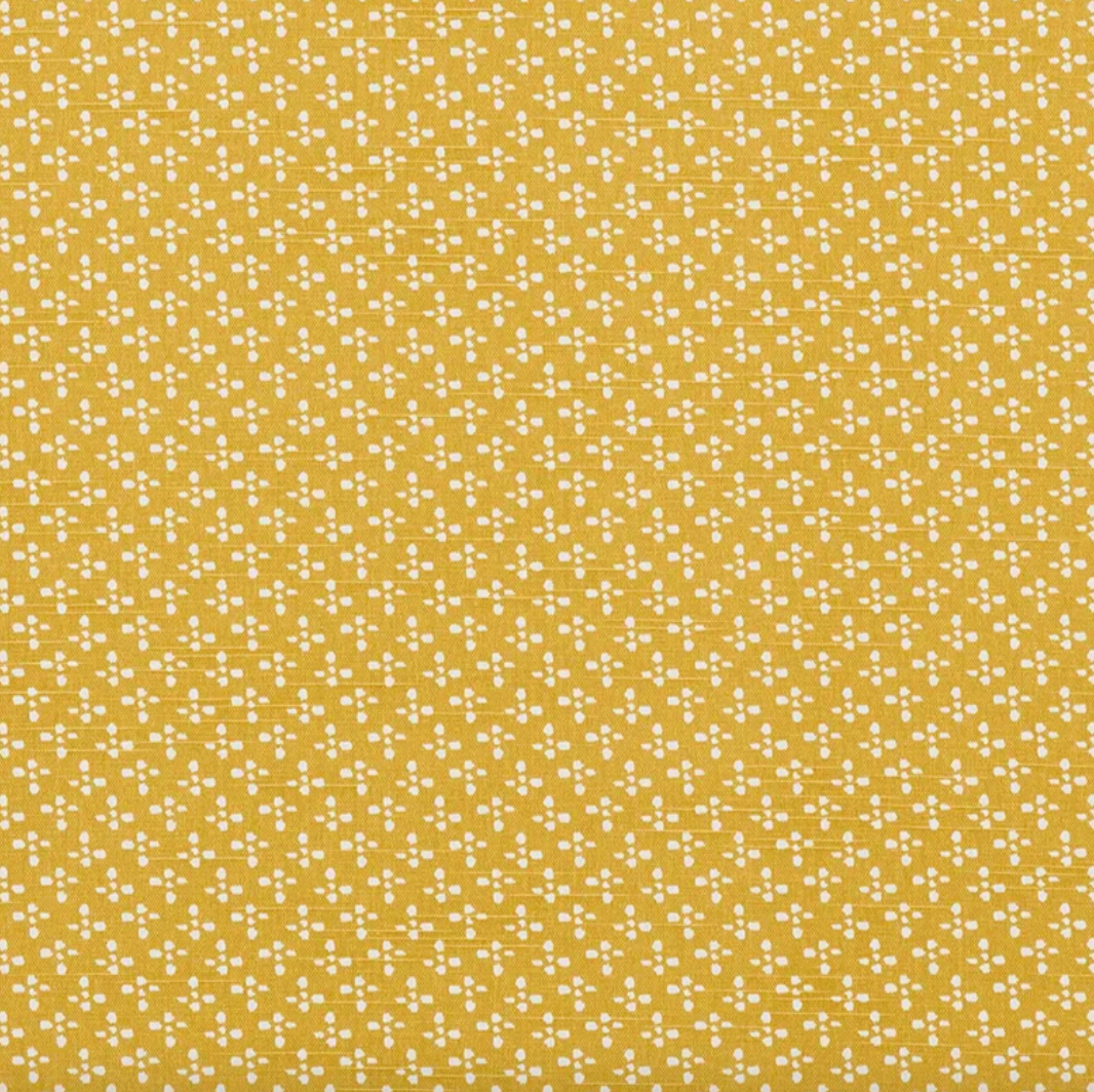 Patterned fabric with small white dots on a mustard yellow background