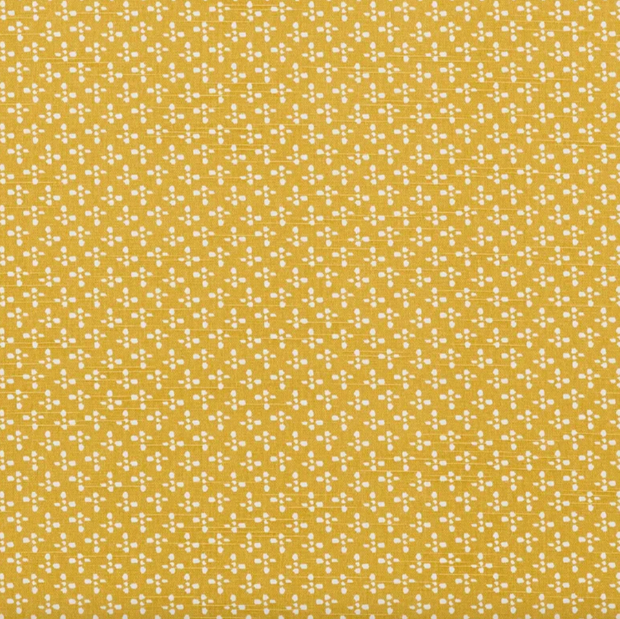 Patterned fabric with small white dots on a mustard yellow background